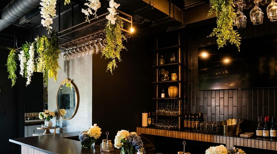 Elegant bar area with dark walls, hanging greenery, a gold mirror, and floral arrangements.