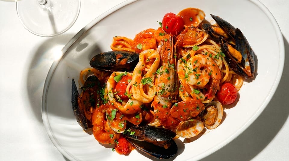 Seafood pasta with shrimp, mussels, clams, squid, and cherry tomatoes in red sauce.