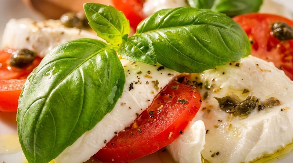 Close-up of fresh Caprese salad with mozzarella, sliced tomatoes, basil, and capers.